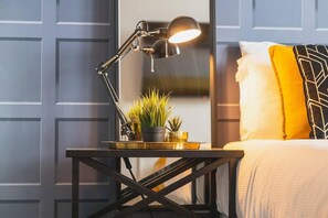A neatly arranged bedroom with a bed, a bedside table with a lamp, and a small potted plant. - Luxury 9ine Stunning Broad Street Apartment (Birmingham)