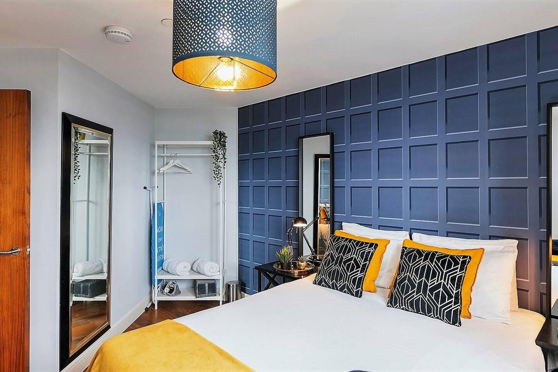 Ein Hotelzimmer mit einem großen Bett, einer Pendelleuchte, einem Kleiderschrank und einem Spiegel.
