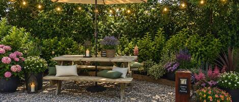 Un espacio al aire libre con mesa de picnic, una toldo y luces colgantes.