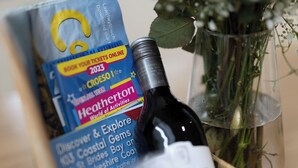 Een brochure met de titel 'Heatherton' en een fles wijn in een mand.