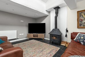 Ein Wohnzimmer mit Kamin, Flachbildfernseher, einer Couch und einem gemusterten Teppich.