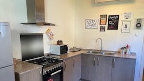A compact kitchen with a gas stove, microwave, and stainless steel sink.