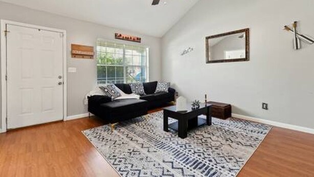 A living room with a black sofa, a coffee table, a patterned rug, a ceiling fan, and a door. - 3-bedroom home in the Mississippi Gulf Coast (Pass Christian)
