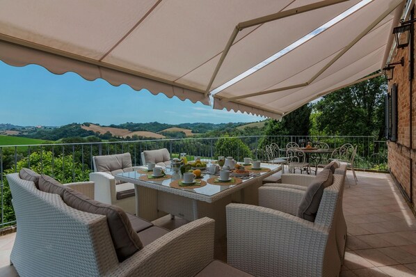 An outdoor patio with a table set for dining, surrounded by wicker chairs, under a canopy. - Villa Mariana - Private villa, 7 bedrooms, pool, A/C, wifi, Beaches 4 km, Marche (Belmonte Piceno)