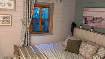 A bedroom with a bed, a window, and a wall-mounted picture.