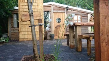 A wooden cabin with a porch, a wooden table, and a potted plant.