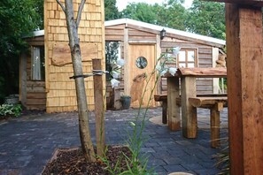 Una cabaña de madera con un porche, una mesa de madera y una planta en maceta.