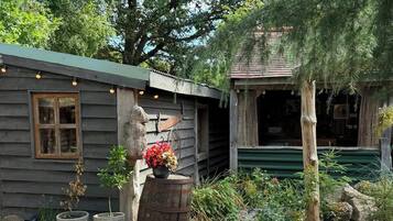 A rustic cabin with a wooden exterior, a stone statue, and a gravel driveway.
