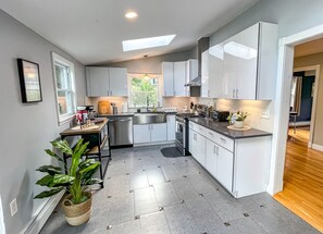 A modern kitchen with white cabinets, a central island, and a skylight. - Majestic Princeton Home • Arcade • Big Yard • 4BR (Princeton)