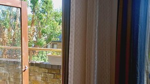A view through a window with a wooden door, a brick wall, and a balcony with a railing. - Lovely 2-bed Apartment in Battersea, London (London)