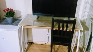 A compact workspace with a flat-screen TV, a small refrigerator, and a chair. - Lovely 2-bed Apartment in Battersea, London (London)