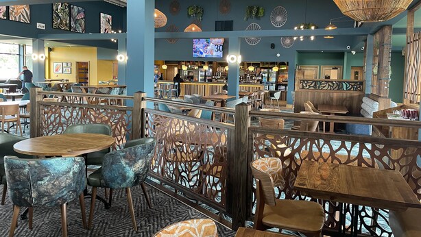 A spacious restaurant with high ceilings, decorative wall art, and a variety of seating options including tables and booths. - Static Caravan - The Dizzard (Holsworthy)