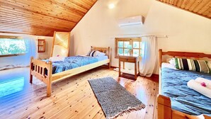 A cozy attic bedroom with wooden floors, a sloped ceiling, and a bed with a view of the outdoors.
