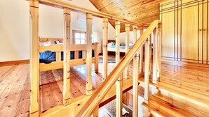 A wooden staircase with a view of a bedroom with bunk beds.