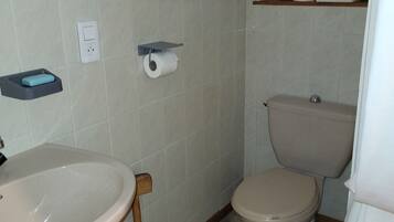 Een kleine badkamer met toilet, wastafel en een plankje met zeepbakje.