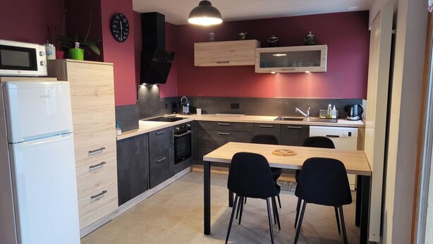 A compact kitchen with a microwave, oven, sink, and a dining area with chairs.