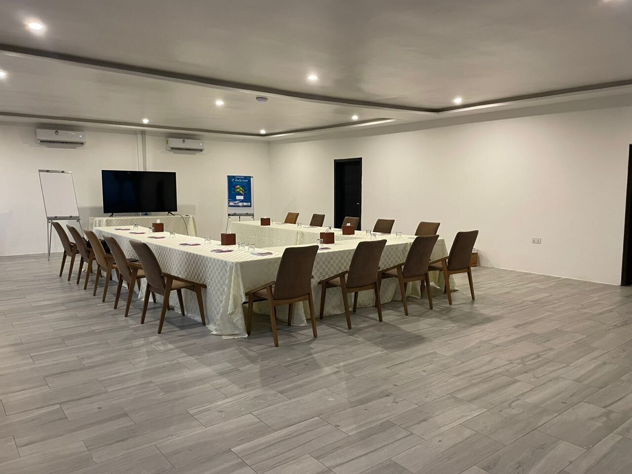 Una sala de conferencias con una larga mesa, sillas, una pizarra y una televisión.