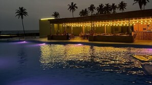 A swimming pool with a bar area and palm trees in the background. - Breezes  Beach Resort (Ekumfi Narkwa)