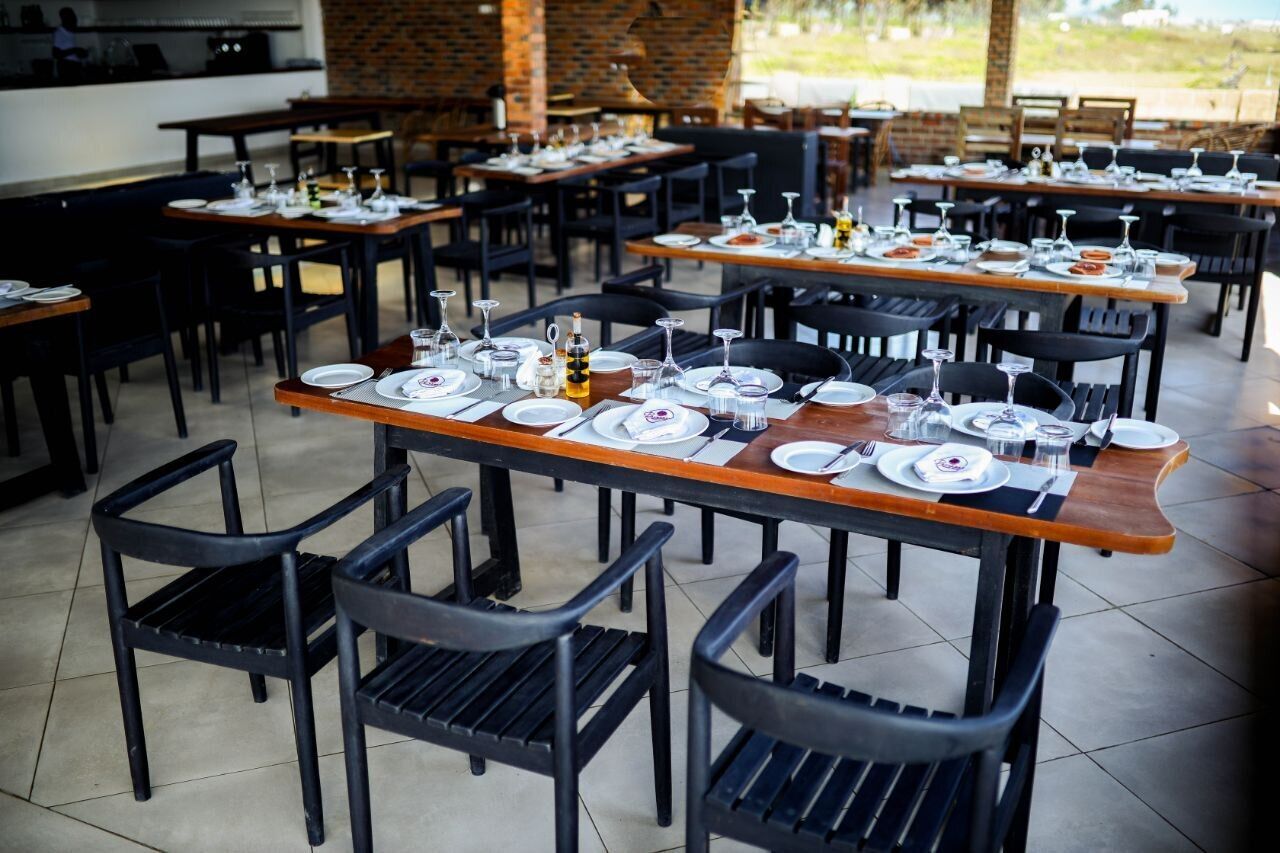 A restaurant with multiple tables set for dining, featuring black chairs and wooden tables.