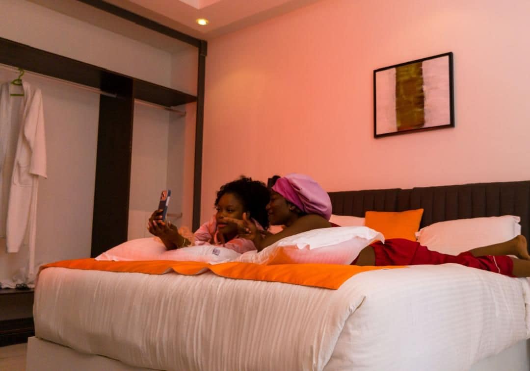 Ein Hotelzimmer mit einem Bett, Kissen, einem Nachttisch und einem an der Wand hängenden Kunstwerk.