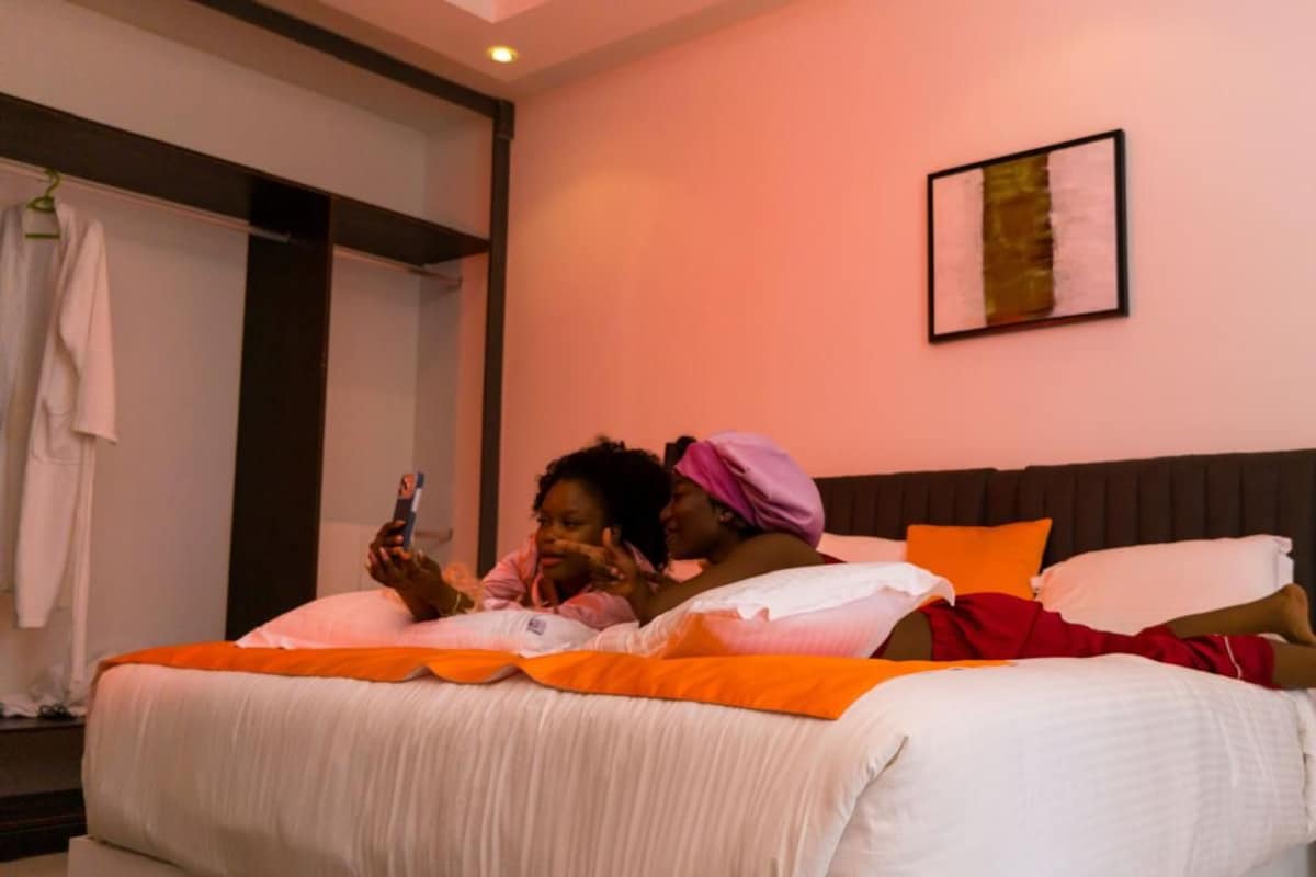 A hotel room with a bed, pillows, a bedside table, and a wall-mounted artwork.