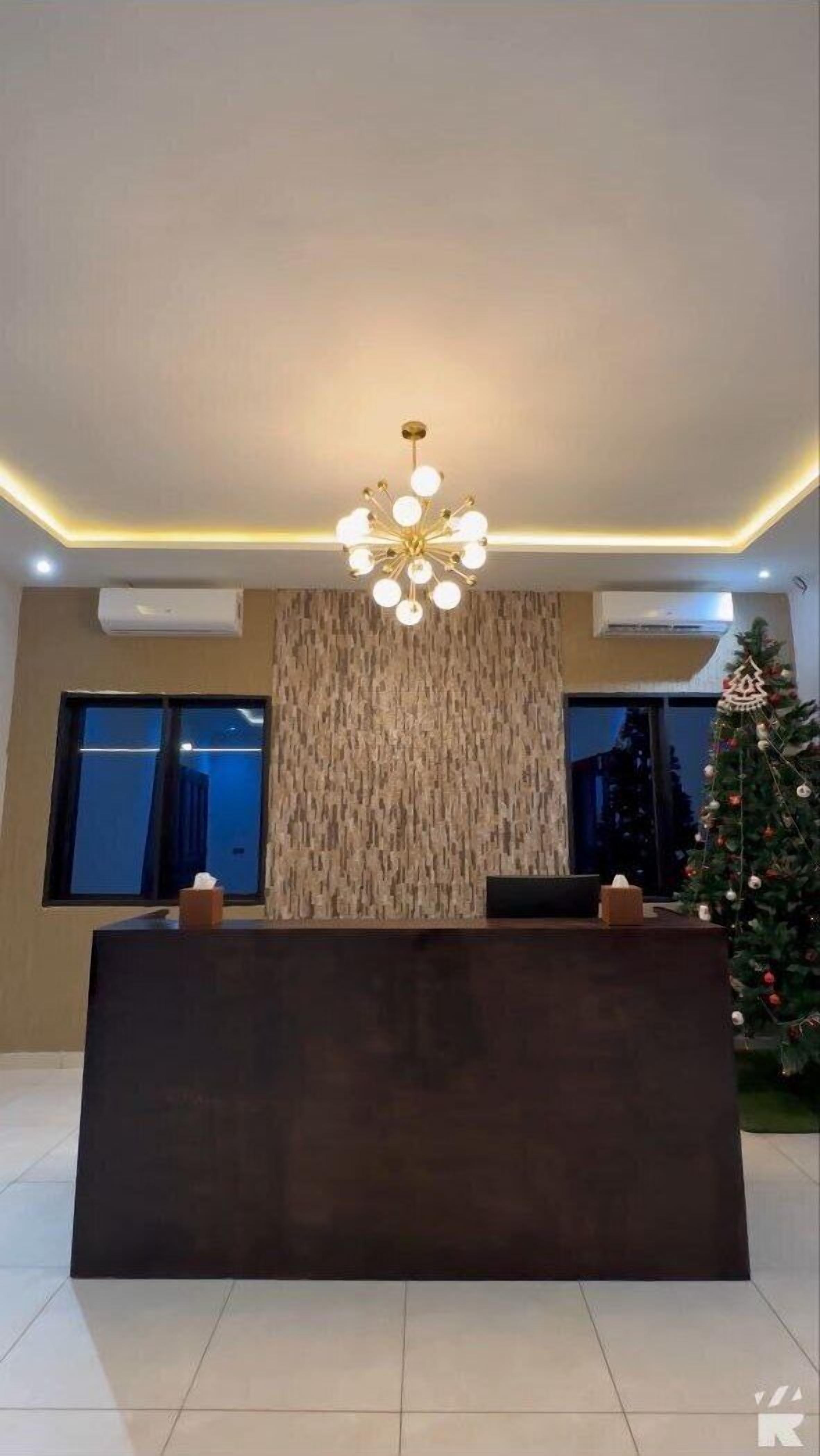 A reception area with a modern chandelier, a textured wall, and a Christmas tree.