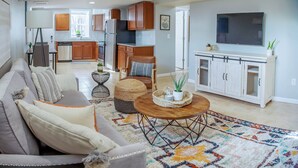 A living room with a sofa, coffee table, and a TV. - Cozy Basement Suite with Full Kitchen, Walk to Edgewood (Atlanta)
