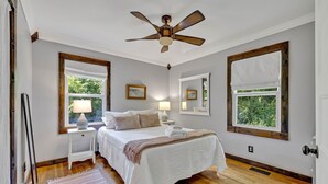 A bedroom with a bed, bedside lamps, a ceiling fan, and large windows. - Serene Hilltop Getaway - Near Lieper's Fork (Santa Fe)