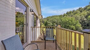 A balcony with a wooden railing, a chair, and a view of a forested hillside. - Serene Hilltop Getaway - Near Lieper's Fork (Santa Fe)