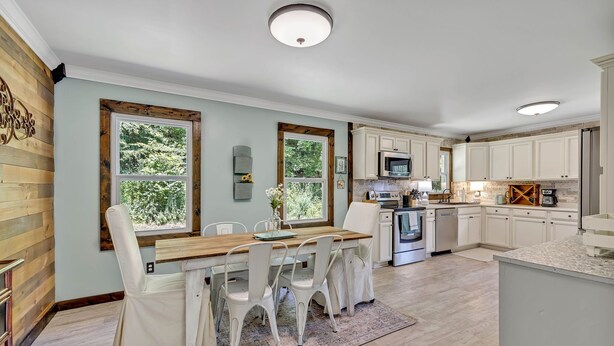 A modern kitchen with white cabinets, a wooden dining table, and a large window. - Serene Hilltop Getaway - Near Lieper's Fork (Santa Fe)