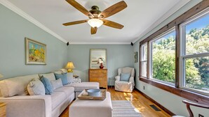 A spacious living room with a large window, a ceiling fan, a sofa set, a wooden coffee table, and a chair. - Serene Hilltop Getaway - Near Lieper's Fork (Santa Fe)