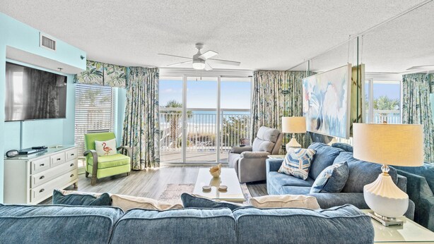 A living room with a sofa, armchairs, a coffee table, and a TV. - Updated Crescent Shores 107 - Oceanfront 3/3 Condo (North Myrtle Beach)