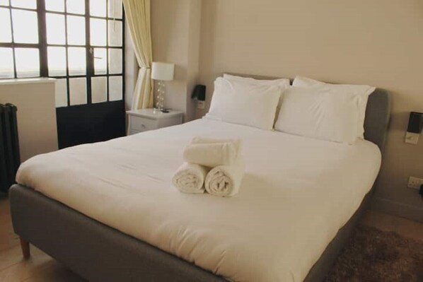 Restful retreat with a made bed, towels, and a window offering a view.