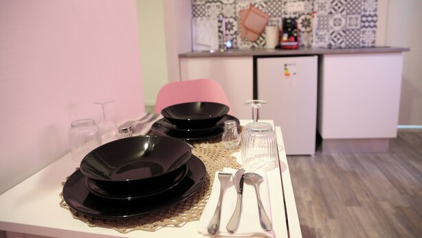 A dining table set with black plates, silverware, and clear glasses, with a microwave and patterned backsplash in the background. - A 5mn du Centre Ville (Saint-Quentin)