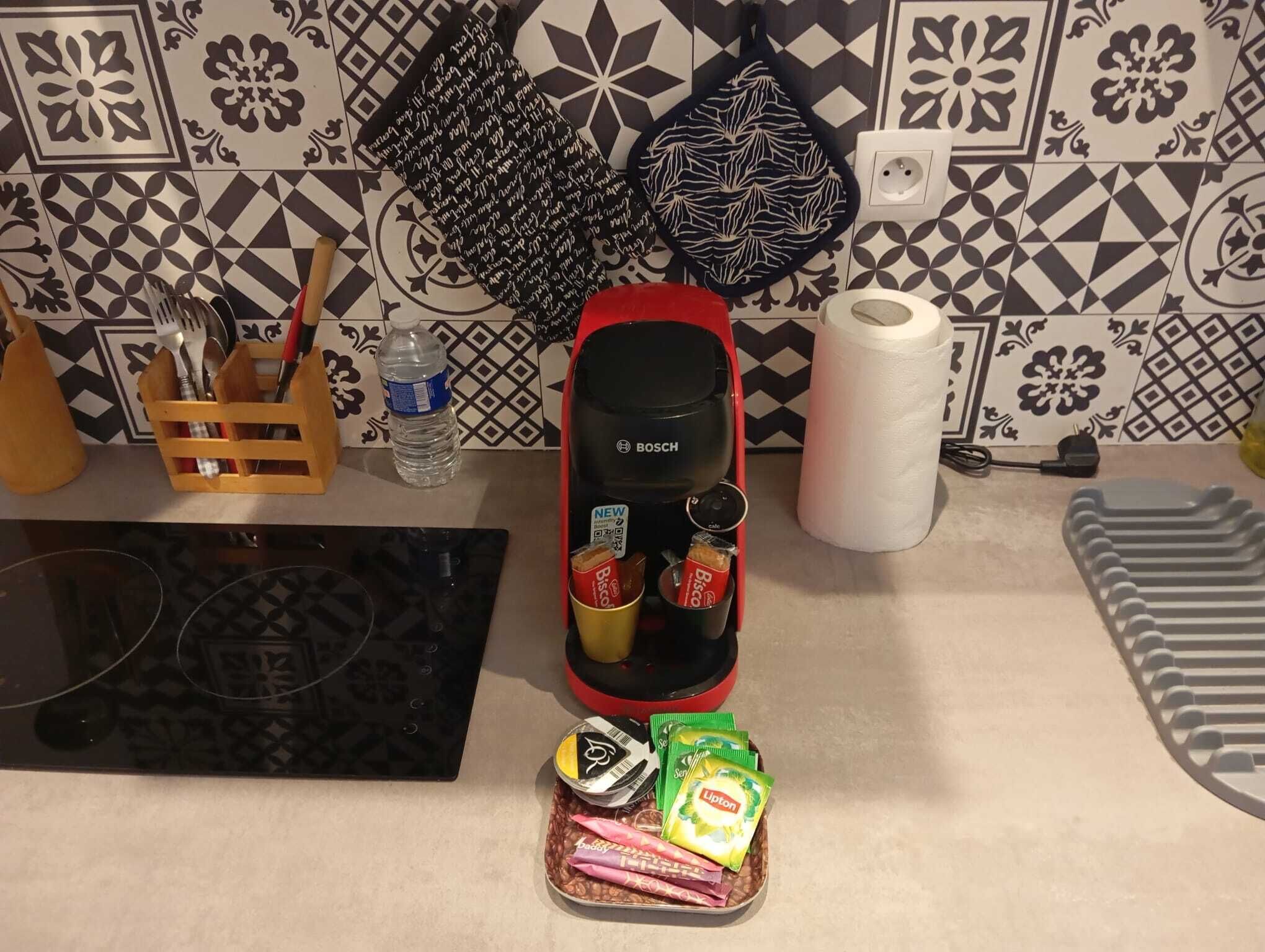 A kitchen counter with a Bosch coffee maker, a water bottle, a red kettle, and a tray with Lipton tea bags.