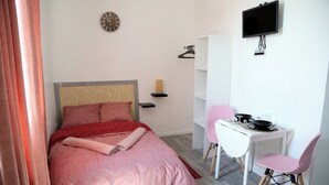 A bedroom with a bed, a desk, a chair, a TV, and a clock. - A 5mn du Centre Ville (Saint-Quentin)