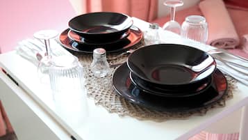 Une table à manger élégamment dressée, avec des assiettes noires, de la vaisselle transparente et des couverts en argent sur une nappe blanche.