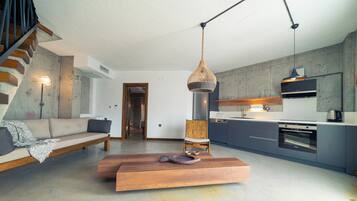 A modern living room with a sofa, a wooden coffee table, and a hanging light fixture.