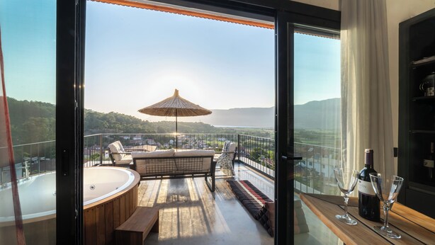 Ein Balkon mit Whirlpool, Sitzgelegenheit und einer Flasche Wein.