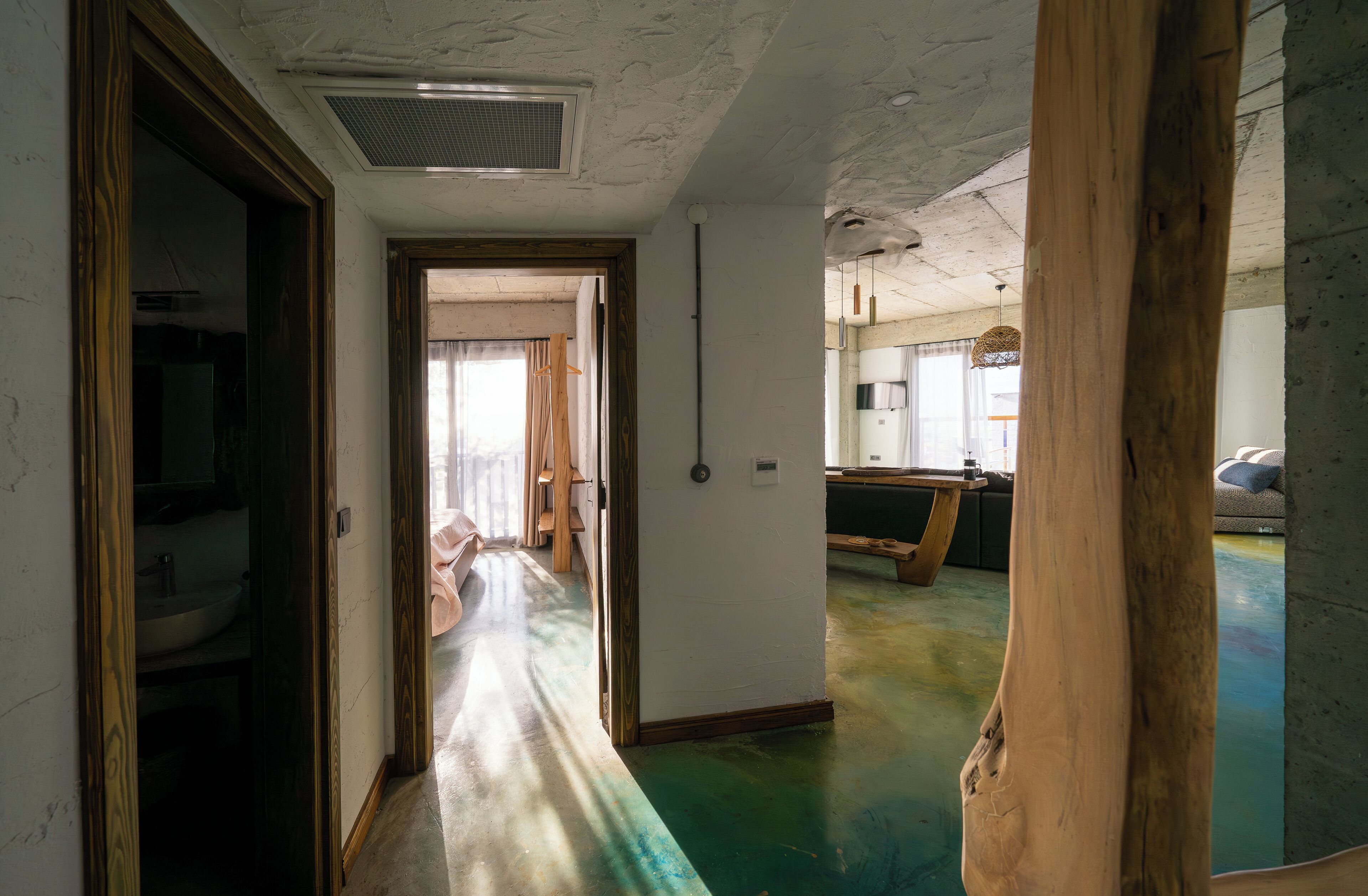 A hallway with a wooden floor, a sink, and a door leading to another room.