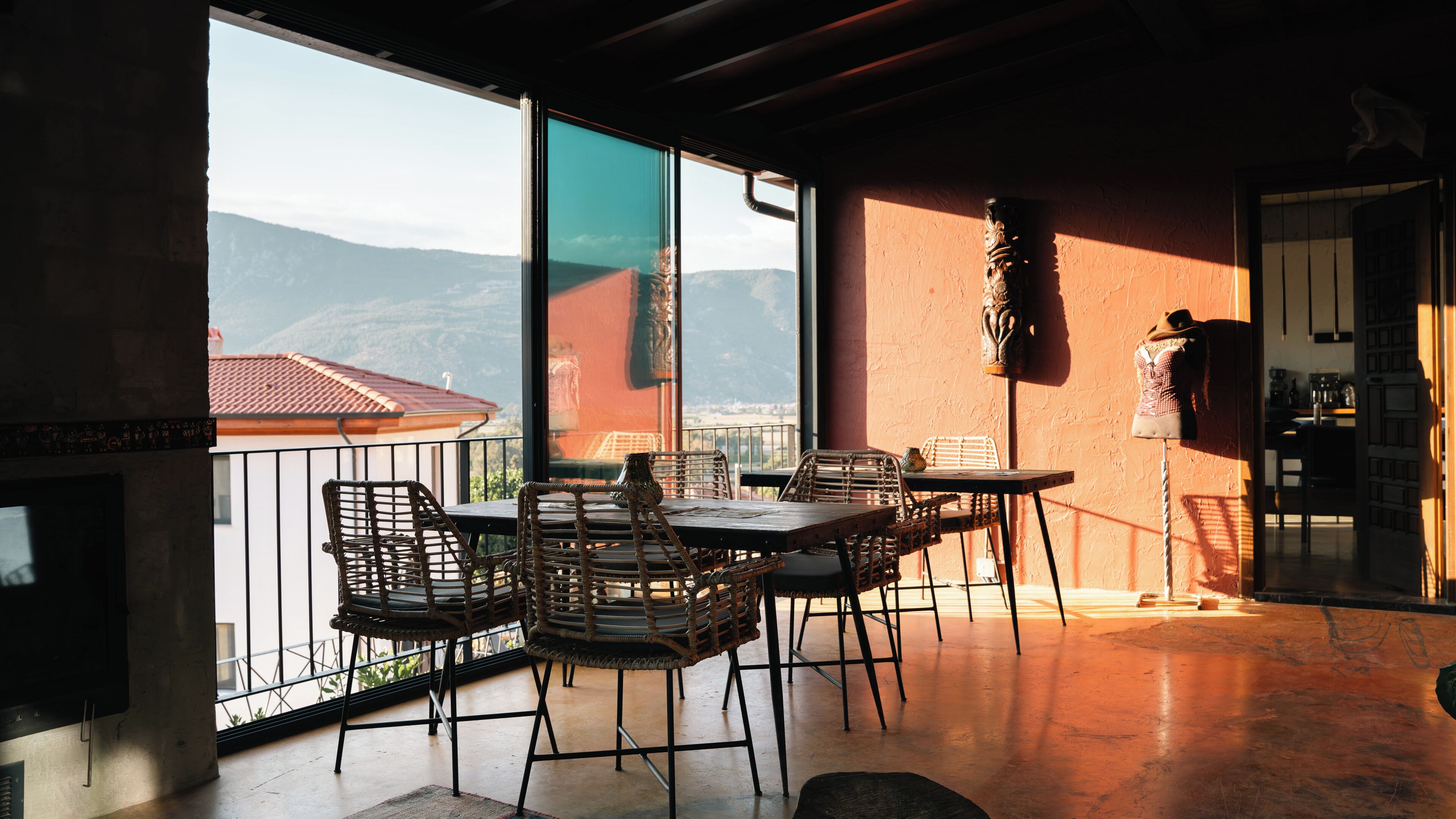 Un balcón con sillas de mimbre y una mesa, con vistas a un paisaje montañoso.