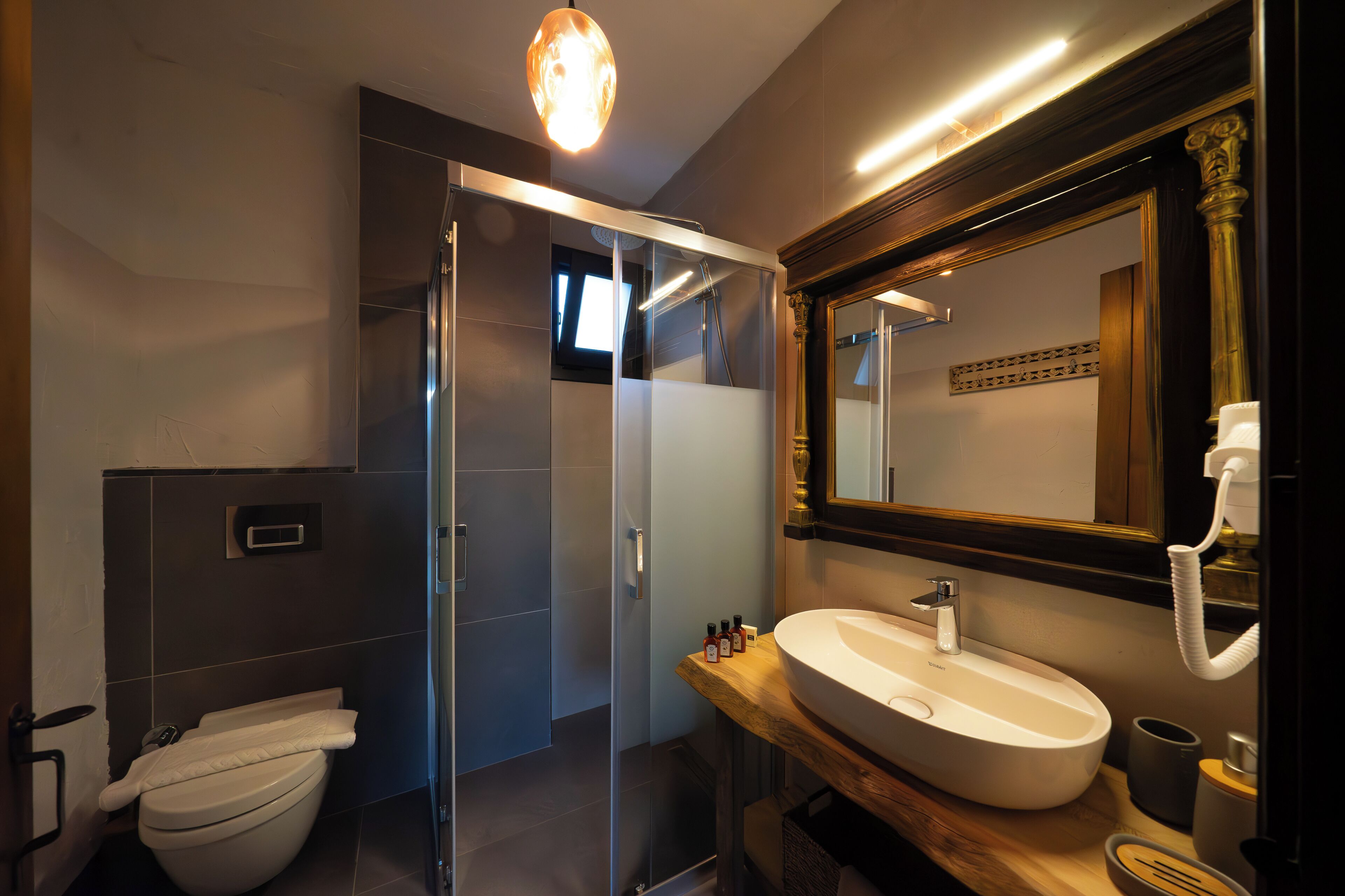 A modern bathroom with a glass-enclosed shower, a white sink, and a large mirror.