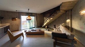 Ein modernes Wohnzimmer mit einer Holzbank, einem Sofa, einem Couchtisch und einer Treppe.