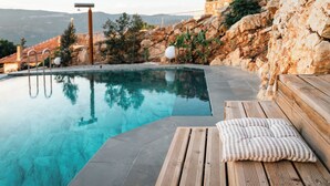 Ein Schwimmbad mit Holzterrasse und Steinmauer.