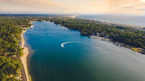 Luchtbeeld van een kustgebied met een groot wateroppervlak, een weg langs de kust en een combinatie van woon- en natuurgebieden.