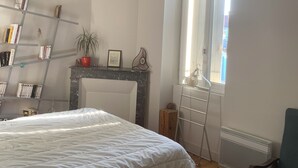 Een slaapkamer met een bed, een boekenkast, een open haard en een raam.