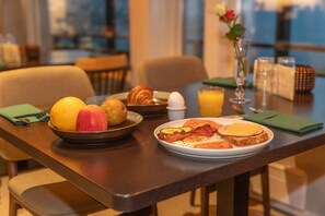 A breakfast setting with a plate of eggs, toast, and vegetables, a bowl of fruits, and a croissant. - Sirdalsvatnet Hotel (Sirdal)