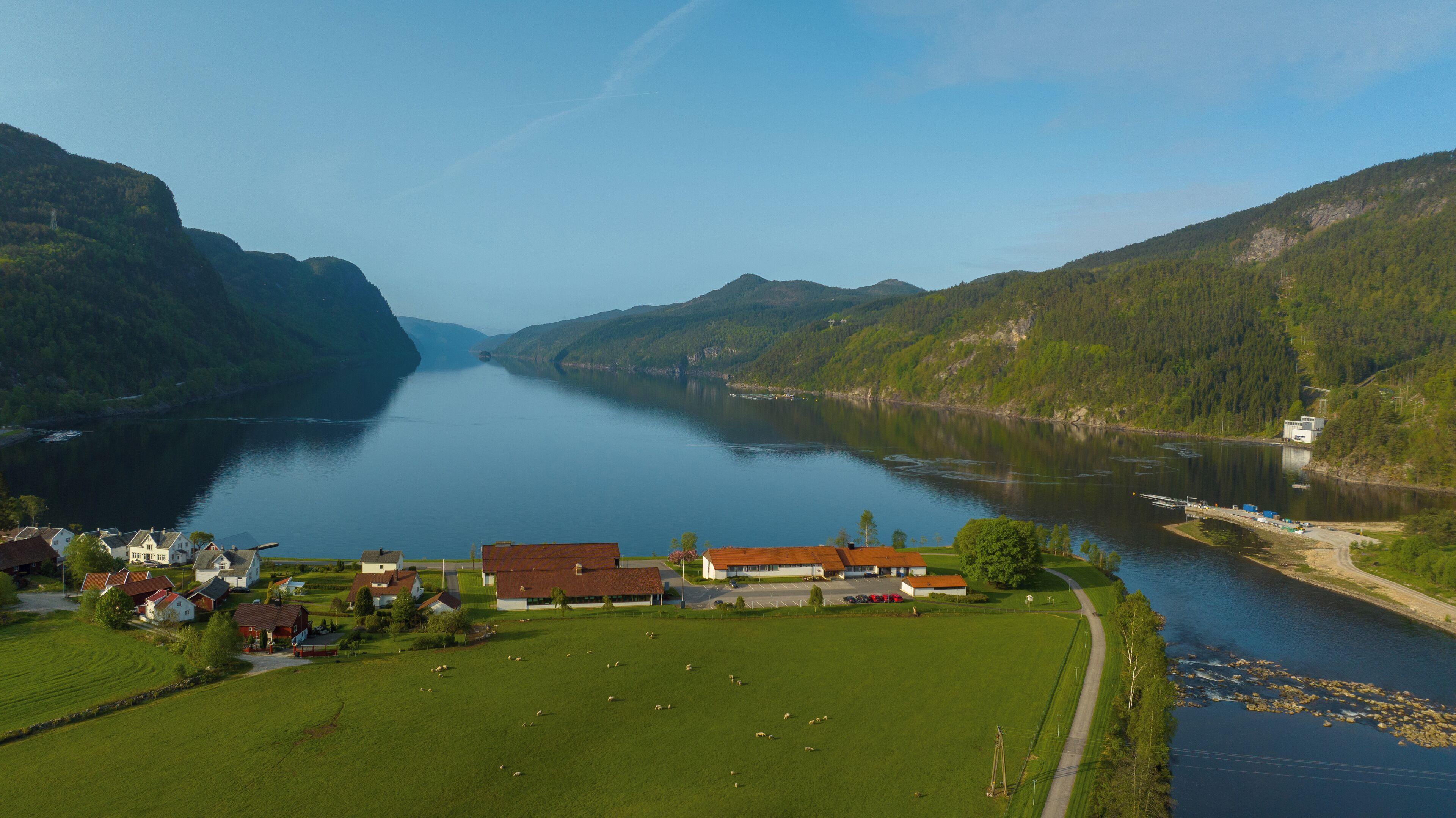A rural landscape with a river, houses, and a small building.