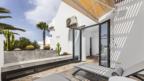 A modern outdoor patio with a built-in grill, a table, and a sunshade.