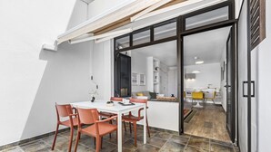 A dining area with a table and chairs, a sliding glass door leading to a kitchen, and a tiled floor.